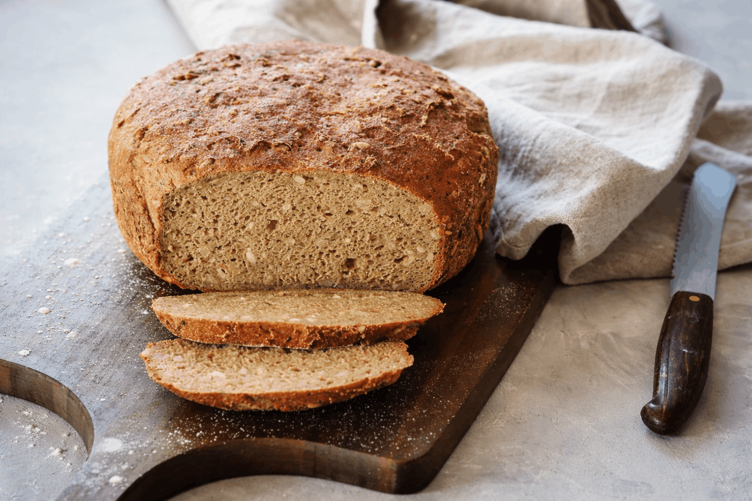 Glutenfreies Zucchini-Topfbrot mit Teffmehl auf Holzbrett, angeschnittene Scheiben sichtbar, rustikale Kruste und saftige Krume.